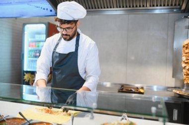 Profesyonel bir aşçı pide ekmeğine malzeme ekler, doğuya özgü bir fast food restoranında shawarma veya kebap hazırlar.