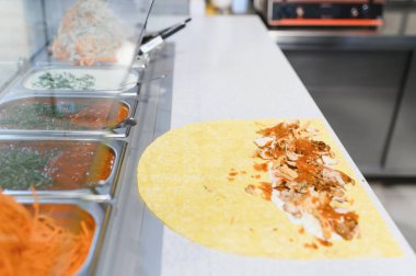 Fast food restoranında soslu ve sebzeli bir lavaşın üzerinde tavuk yahnisi ya da kebap hazırlıyorum.