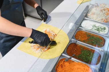 Aşçı, lavaş ya da pita ekmeğine rendelenmiş havuç ve beyaz lahana ekliyor.