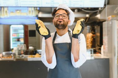 Siyah eldivenli komik şef iki lezzetli shawarma tutuyor kebap lokantasında öpüşüyor.