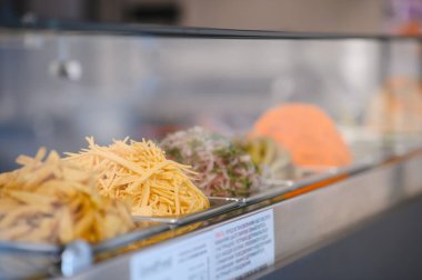 Camın arkasındaki metal kaplarda çeşitli taze malzemeler sergileniyor. Sokak yemeklerinde kullanılmaya hazır.