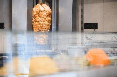 Tükürüğün üzerinde dönen lezzetli shawarma eti, bir sokak lokantasında yemek pişirmek, pide veya başka bir ekmeğin içinde servis edilmeye hazır olmak.