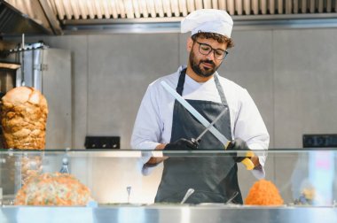 Profesyonel aşçı bıçak keskinleştiriyor. Bir fast food restoranında lezzetli shawarma ya da kebap hazırlamaya hazırlanıyor.