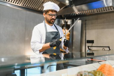 Profesyonel aşçı bıçakları biler. Ticari bir mutfakta shawarma ya da kebap için et dilimlemeye hazırlanır.