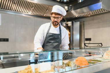 Orta Doğulu şef cam vitrinde taze malzemeler hazırlıyor, fast food restoranında lezzetli shawarma ya da kebap servis etmeye hazırlanıyor.