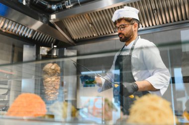 Profesyonel şef kıvrımlı bir tükürükten shawarma etini ustaca dilimliyor, lezzetli ve otantik bir orta doğu sokak yemeği hazırlıyor.