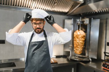 Kendine güveni tam bir aşçı. Ticari bir mutfakta, lezzetli bir shawarma servis etmeye hazırlanıyor.