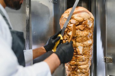 Büyük bir bıçak ve spatula kullanarak, bir sokak lokantasında dönen bir tükürükten kızartılmış et dilimlemek.