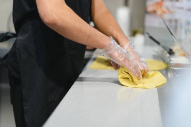 Eldiven giyen aşçı dolgulu bir ekmek sarıyor, profesyonel bir mutfakta shawarma ya da kebap yapıyor.