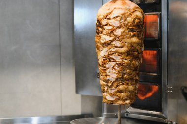 Ticari bir fırında dikey tükürükte pişen büyük bir shawarma eti mutfakta ağız sulandıran aromalar yaratıyor.