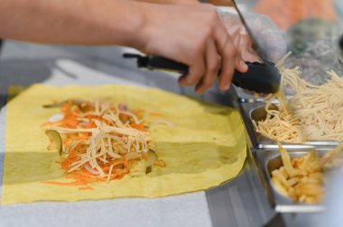 Doğu mutfağında uzmanlaşmış bir fast food restoranında lezzetli bir shawarma ya da kebap pişirip maşayla peynir eklemek.