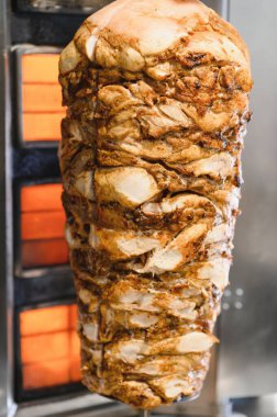 Sulu tavuk shawarma, düşey tükürük kızartma makinesinde dönüyor. Isıtıcı elementin önünde yavaşça ve eşit bir şekilde pişiyor.