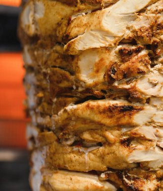 Baharatlı tavuk shawarma yakın plan dikey tükürük üzerinde dönen, yavaş yavaş pişirme ve cazip bir sokak yemeği deneyimi yaratmak