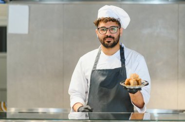 Kendine güvenen şef leziz shawarma eti sunuyor, orta doğu mutfağı ve sokak yemekleri hazırlama konusunda uzmanlık gösteriyor.