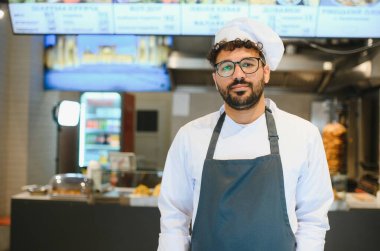 Orta Doğulu şef kebap lokantasında poz veriyor. Küçük bir sokak yemeği ve shawarma restoranı sahibi.