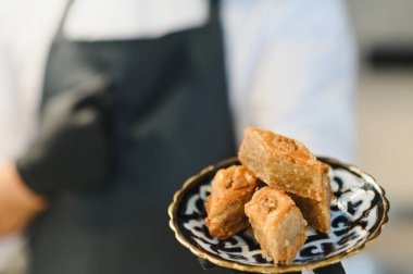 Pasta şefi süslemeli bir tabakta lezzetli, taze yapılmış baklava sunar. Orta doğu ya da Akdeniz mutfağında uzmanlık gösterir.
