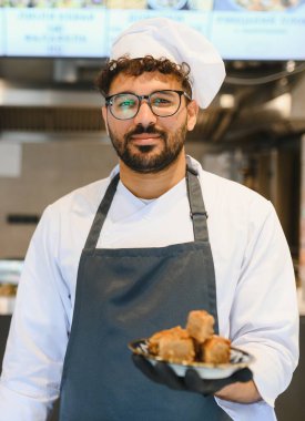 Doğu lokantasının mutfağında baklava gösteren kendine güvenen şef, sokak yemeklerini ve Arap mutfağını temsil ediyor.