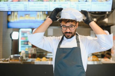 Genç aşçı, bir sokak lokantasında çalışırken elbisesini düzeltiyor. Lezzetli doğu mutfağı servis etmeye hazırlanıyor.