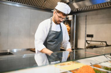 Profesyonel aşçı, fast food restoranının mutfağında lezzetli bir orta doğu yemeği hazırlıyor. Mutfak uzmanlığı ve geleneği sergiliyor.