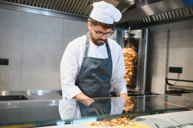 Profesyonel aşçı, pide ekmeğine et ekliyor, doğu mutfağında uzmanlaşmış bir sokak lokantasında çalışıyor.