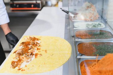 Lavaş ya da pita ekmeğine tavuk ve sos eklemek, fast food restoranında çeşitli malzemelerle bir shawarma ya da kebap hazırlamak.