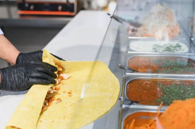 Bir fast food restoranında çeşitli malzemeler ve soslarla nefis bir shawarma ya da kebap sarması yapar.