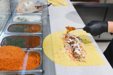 Lezzetli shawarma ya da kebap hazırlamak, et ve sebzelere sos eklemek, yemek festivali ya da sokak yemekleri pazarında