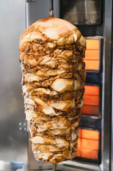 Sulu tavuk shawarma dikey bir tükürük üzerinde dönüyor, yavaş yavaş pişiyor ve ızgara restoranda kızarıyor, sokak yemeği olarak servis edilmeye hazır.