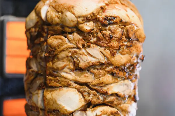 Lezzetli tavuk shawarma ya da kebap eti bir sokak lokantasında elektrikli ısıtıcı tarafından dikey bir rostoda pişiriliyor.
