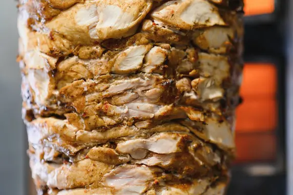 Sulu tavuk shawarma, dikey bir tükürük üzerinde dönüyor, bir restoranda yavaşça ve eşit bir şekilde pişiyor, pidanın içinde servis edilmeye ya da paketlenmeye hazır.