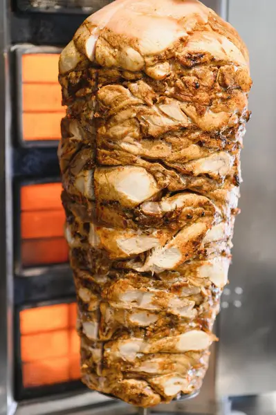 Sulu tavuk shawarma, düşey tükürük kızartma makinesinde dönüyor. Isıtıcı elementin önünde yavaşça ve eşit bir şekilde pişiyor.