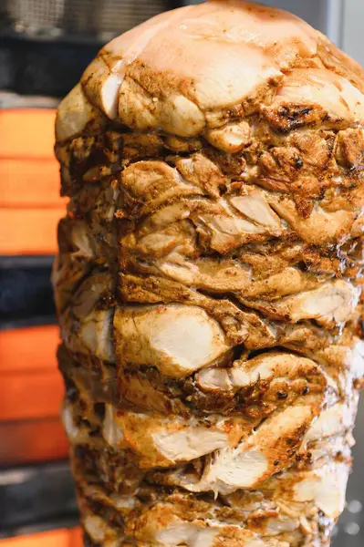 Sulu tavuk shawarma dikey bir tükürük üzerinde dönüyor, yavaşça pişiriyor ve ağız sulandırıcı aromalar yayıyor, dayanılmaz sokak yemekleri yaratıyor.