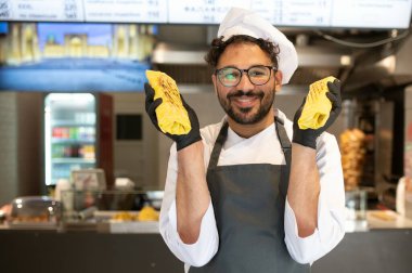 Mutlu aşçı, siyah eldiven ve toka giymiş iki lezzetli shawarma 'yı sokak yemeklerinde çalışırken gösteriyor.