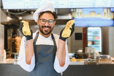 Şark mutfağında uzmanlaşmış bir fast food restoranında çalışırken iki lezzetli shawarma gösteren mutlu bir aşçı.