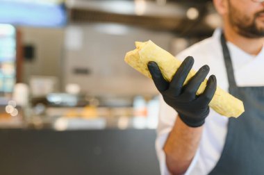 Şef siyah eldiven giyip fast food restoranının mutfağında lezzetli bir shawarma hazırlıyor.