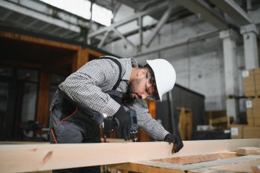 Ortadoğulu marangoz, inşaat atölyesindeki prefabrik modüler ev için kablosuz matkap montajı yapıyor.