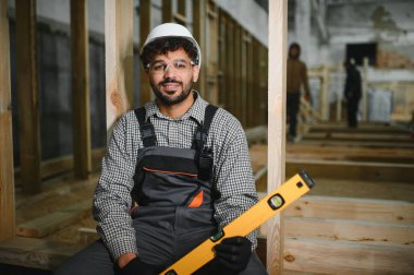 Arap inşaat işçisi bir atölyede bir modüler ev montajı, bir seviyeli araç tutmak, inşaat işçiliği ve hassasiyet gösterme