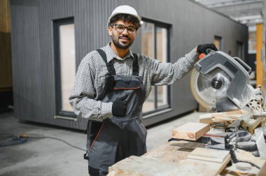 Daire testere kullanan marangoz prefabrik modüler ev inşaatı için tahta kesiyor.