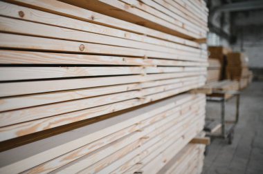 Eşsiz boyutta kereste yığınları düzgün istiflenmiş, bir marangoz fabrikasında işleme ve mobilya üretiminde kullanılmaya hazır görsel olarak çekici bir kalıp oluşturmuş.