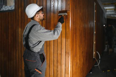 Modüler ev üretim atölyesinde prefabrik ahşap duvar bölümünü cilalayan profesyonel marangoz.