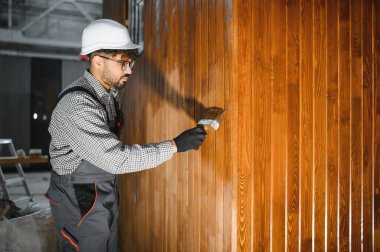 Bir inşaat atölyesinde ahşap kalasları cilalayan odaklanmış marangoz prefabrik ev malzemelerinin kalitesini yükseltiyor.