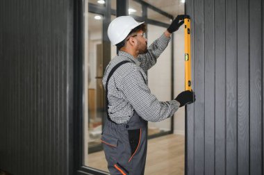 Modüler ev inşaatı sırasında ruhsal seviyeyi kullanarak hassas dikey hizalamayı sağlayan yetenekli işçiler, prefabrik bina kalitesini ve hassasiyetini vurguluyor.