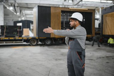 Modüler evler montajını yöneten, prefabrik konutlarda modern teknikler sergileyen usta bir Arap işçi.