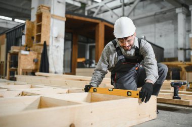 Ruh seviyesini kullanan marangoz prefabrik ev inşaatında hassasiyet sağlıyor, modüler binalarda kalite kontrolünü vurguluyor.