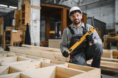 Yetenekli marangoz, bir marangoz fabrikasında modüler ev inşaatı sırasında hassasiyet sağlamak için ruh seviyesini kullanır.
