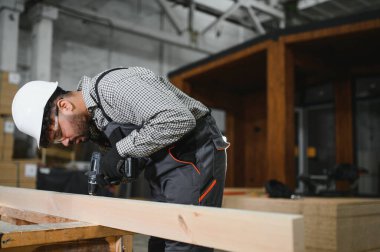 Bir inşaat atölyesinde çalışan işçiler modüler ev bileşenlerini ustalıkla birleştiriyor, modern inşaatlarda ustalık ve hassasiyet sergiliyorlar.