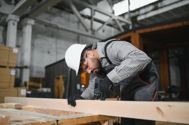 Yoğunlaştırılmış marangoz ahşap bir kalas deliyor, çalışkan bir atölyede ustalık ve hassasiyet sergiliyor.