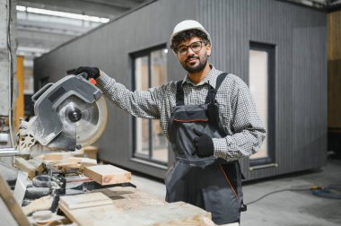 Becerikli bir marangoz dairesel testere kullanırken baş parmak kaldırıyor, marangozlukta uzmanlık ve hassasiyet gösteriyor.