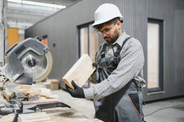 Bir inşaat atölyesinde profesyonel işçi. Modüler ev yapımı, sergilenen uzmanlık ve odaklanma için ahşap malzemelerle ilgileniyor.