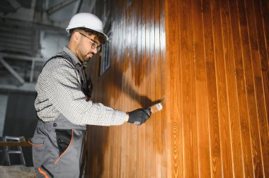 Modüler ev inşaat atölyesinde prefabrik ahşap duvar bölümünü cilalayan odaklanmış marangoz.